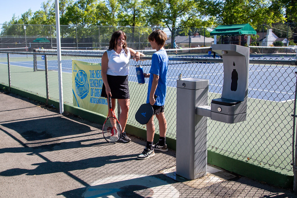 Outdoor Drinking Fountain at a School Tennis Court with Boy and Girl Talking