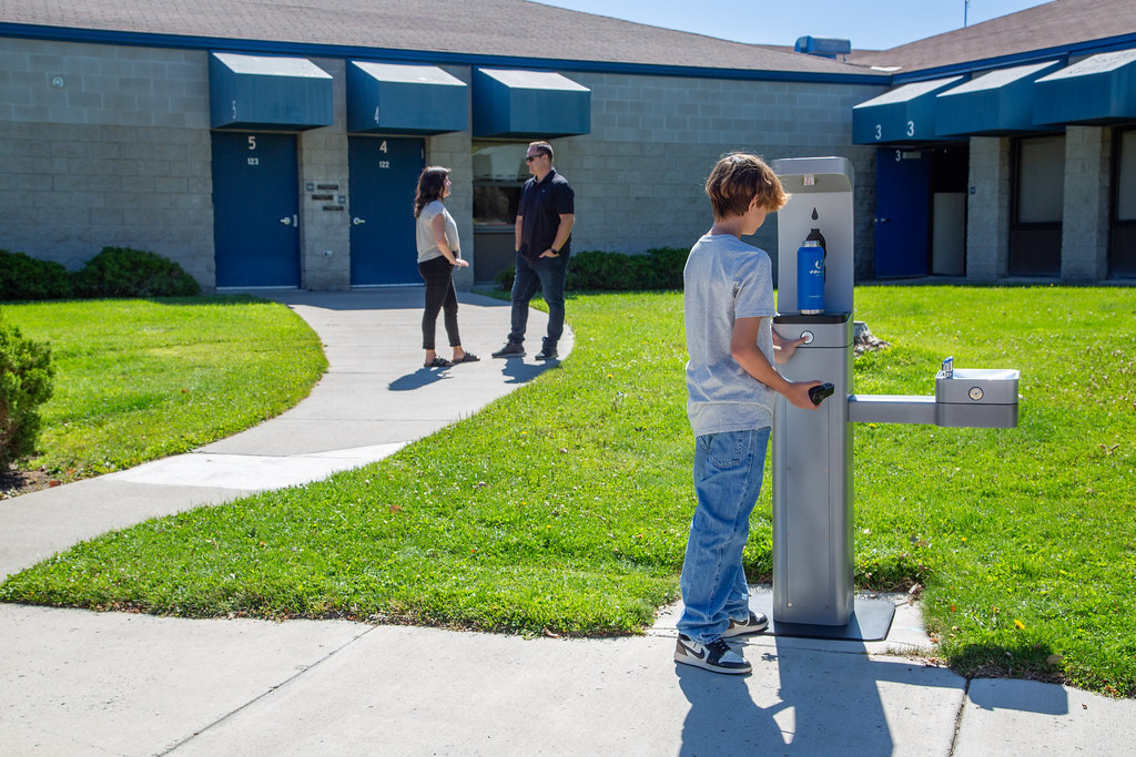 Outdoor Drinking Fountain at a School with Students in Background